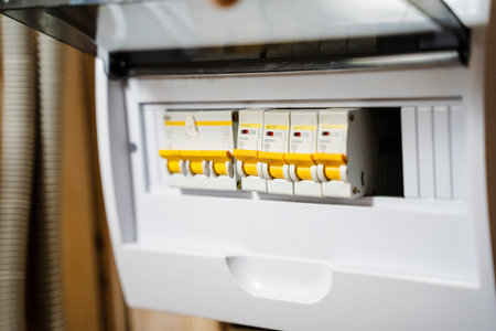 A detailed view of an electrical circuit breaker panel featuring multiple switches for home...