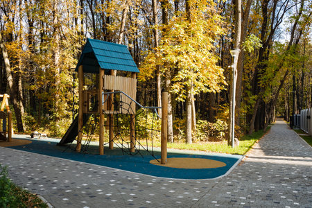 A picturesque playground with a charming wooden structure is nestled in a vibrant forest of colorful...