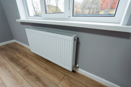 This modern interior features a sleek white radiator under large windows, offering warmth and comfort to create a stylish living area ideal for relaxation and spending quality time togetherの写真素材