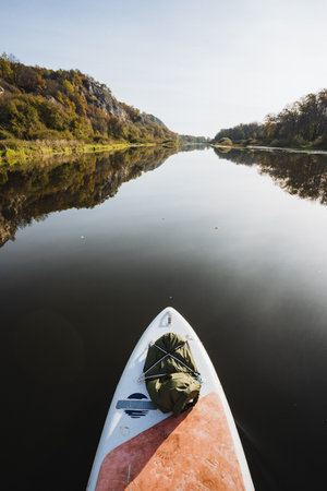 Enjoy the tranquility of paddleboarding on a serene river surrounded by greenery. Its perfect for outdoor adventures and relaxation, offering a refreshing escape from everyday stressの写真素材