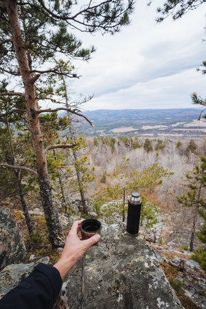 Solo mountain coffee, Solitary adventurer enjoys warm beverage amidst breathtaking wilderness scenery, Quiet moment of reflection and warmth during remote mountain hike at high elevationの写真素材