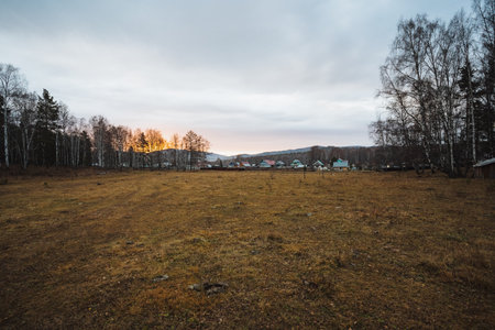 Calm rural scenery with open spaces, Quiet agricultural landscape extending towards small village in distance, Tranquil rural environment featuring expansive fields and serene sky at duskの写真素材