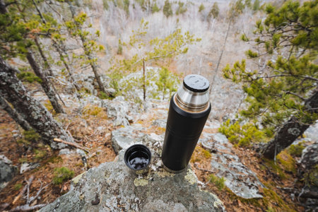 Scenic outdoor setting, Peaceful natural environment with moss and cloudy sky overhead, Serene outdoor tableau with beverage container on rugged cliff face amidst moss and overcast weatherの写真素材