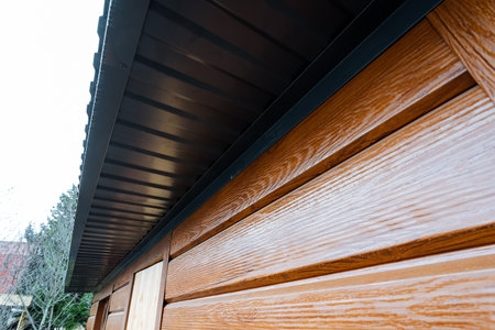 diagonal perspective of wood siding and soffit highlighting texture and repeated grooves, texture study for material catalog with natural light and subtle reflections, outdoor moodの写真素材