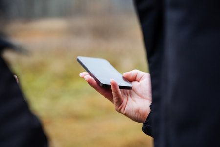 hands with phone, professional outdoors smartphone use, executive checks messages in park settingの写真素材