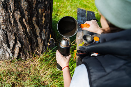 Experience the joy of brewing a delightful cup of coffee outdoors, nestled beside a magnificent and beautiful tree, which truly captures the essence of natures peace and stunning tranquilityの写真素材