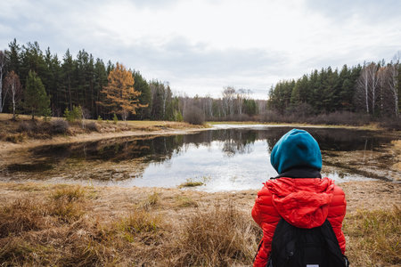 Young adventurer beside water, Child in colorful clothing investigates natural environment with curiosity, Young child wearing vibrant jacket explores outdoors with confidence and keenの写真素材