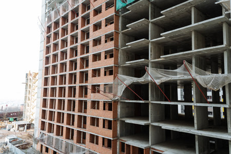 partially constructed midrise building with exposed concrete and brick facades, scaffolding and...