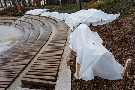 empty theater beneath cold snow, silent performance space with snow covering seats and gray clouds overhead, deserted stage area blanketed in snow with scattered leaves against dull gray skyの写真素材