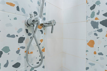 terrazzo shower wall with chrome fixtures, bright tiled niche showcasing popular terrazzo pattern...
