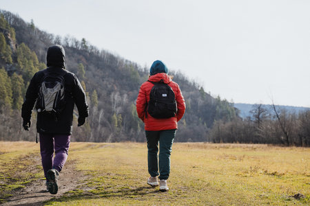 Hikers trekking outdoors, Fitness enthusiasts traverse verdant landscape under cloudy sky, Group of athletic hikers move swiftly through grassy terrain amidst mountain backdrop and overcastの写真素材