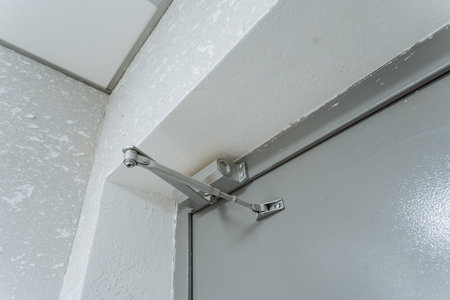 adjustable metal door closer system, closeup of door frame locking and automatic closing device,...