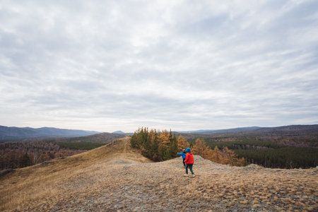 Hikers navigating terrain, Adventurers trekking through rugged landscape carefully, Group of outdoor enthusiasts skillfully traversing challenging terrain amidst autumn scenery and cloudyの写真素材