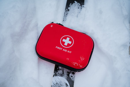 Red First Aid Kit Resting On Ski In Deep Snow, Closeup Emphasizing Rugged Case And Accessibility...