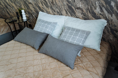 Neutral Layered Pillows On Bed, Quilted Beige Comforter With Gray And Blue Lumbar Cushions, Textured...