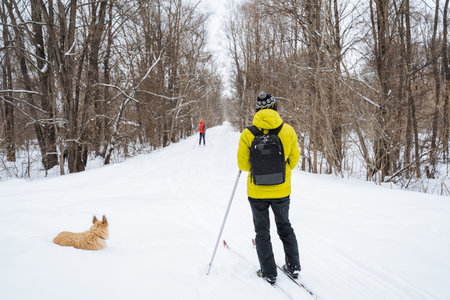 Skier And Dog. Friendly Skier Resting With Pet In Snow. Relaxed Outdoor Moment Between Skier And Dog...