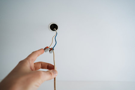 Closeup Of DIY Electrical Installation Process. Person Connecting Wires To Ceiling Fixture With...