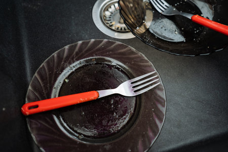 Focus On Utensil And Stained Dish. Detailed Image Of Worn Glass Plate And Silverware. Closeup Of Fork With Red Handle On Greasy Stained Dish Revealing Textures And Residualsの写真素材