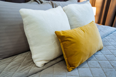 Colorful bedroom accent. Bright cushion enhances bedroom style. Vivid yellow pillow complements modern bedroom decor. Eyecatching mustard cushion adds vibrancy to neutral bedding ensemble
