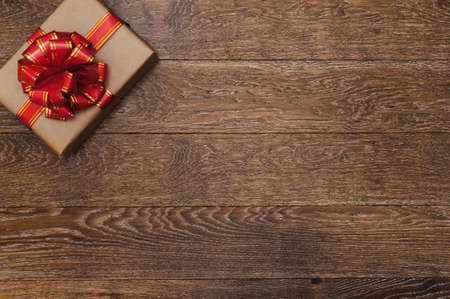 Gift with a red ribbon and bow on a dark wooden background. Christmas decorationsの写真素材