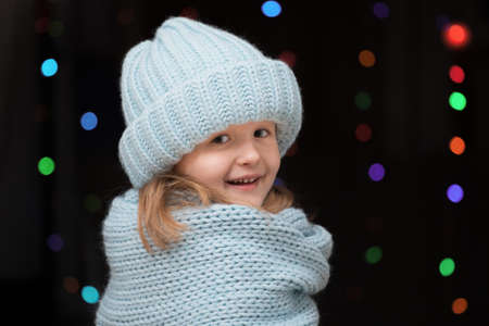 Portrait of a kid girl in a winter blue knitted cap and a scarfの写真素材
