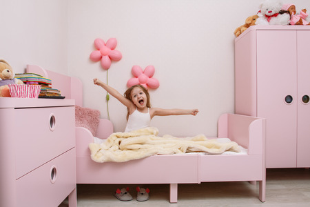 little girl wakes up in the morning in the children's bedroomの写真素材