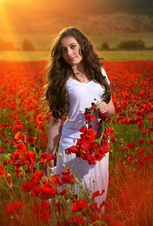 beautiful girl in a poppy field at sunsetの写真素材