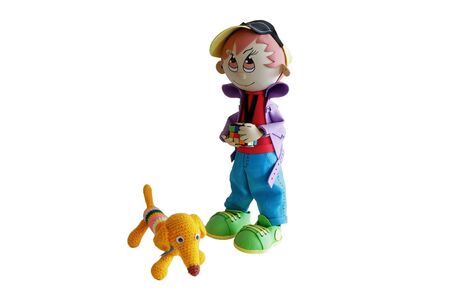 A puppet boy in blue pants, green sneakers and a yellow hat. The doll has a toy in his hand. There's a dog next to the boy made of yellow yarn. Isolated on a white background.の写真素材