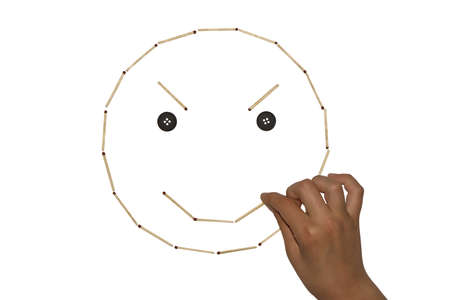 The hand lays out a picture of matches. A mocking face with button eyes. I create my own mood. Isolated on a white backgroundの写真素材