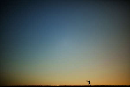 Silhouette of a young photographer during the sunset.の写真素材