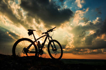 Beautiful scene of bike on sunset in mountains with deep cloudsの写真素材