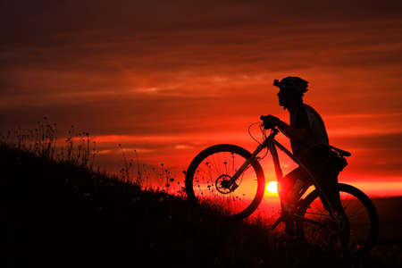 Silhouette of a bike on sky background on sunsetの写真素材
