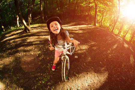 Portrait of a little girl on a bicycle in summer park outdoorsの写真素材