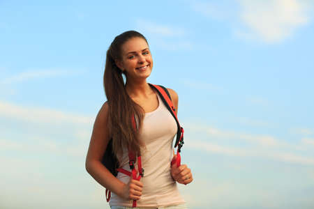 Happy sportswoman with red backpack walking on sunset summer.の写真素材