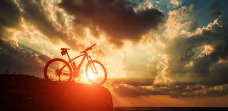 Beautiful scene of bike on sunset in mountains with deep cloudsの写真素材