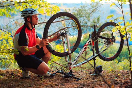 Man cyclist repairing a bike in the wood at afternoonの写真素材