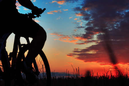 Silhouette of a bike on sky background on sunsetの写真素材