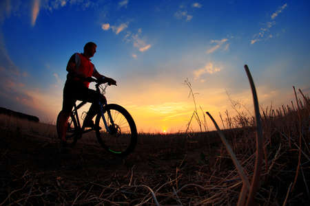 Silhouette of a bike on sky background on sunsetの写真素材