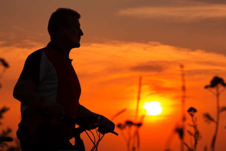 Silhouette of a bike on sky background on sunsetの写真素材