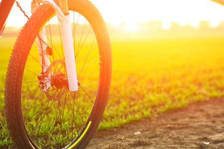 Beautiful close up scene of bicycle at sunset, silhouette of bike forward to sun, wonderful rural...