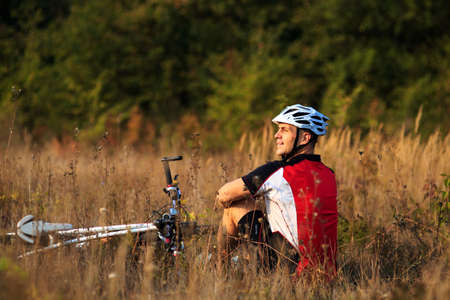 cyclist with bike relax front view of the sunny autumn parkの写真素材