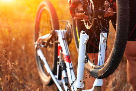 Bike repair. Young man repairing mountain bike in the forest