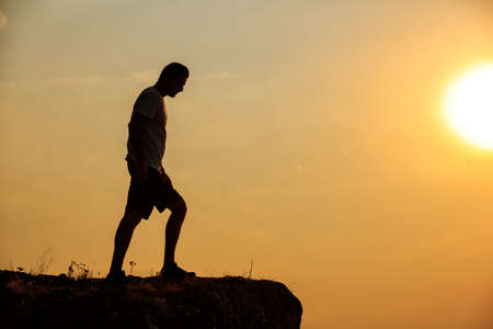 Silhouette of Man stands near the cross on top of mountainの写真素材