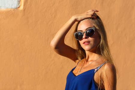 Fashion young woman with long legs in summer clothes against wall. Outdoors. Urban lifestyle shot.