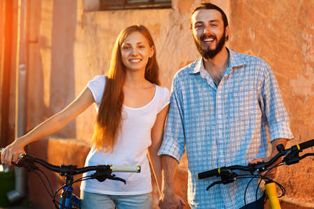 Portrait of happy young couple of bicyclists smiling in the street
