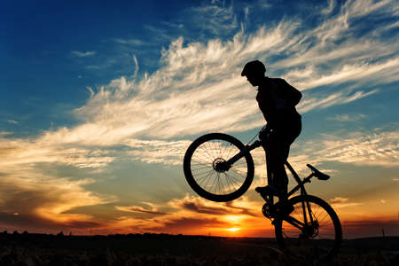 Silhouette of a man on muontain-bike, sunsetの写真素材