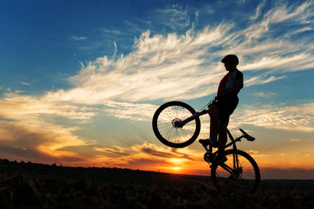 Silhouette of a man on muontain-bike, sunsetの写真素材