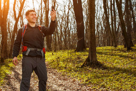 Man hiker taking photo with smart phone at spring forestの写真素材