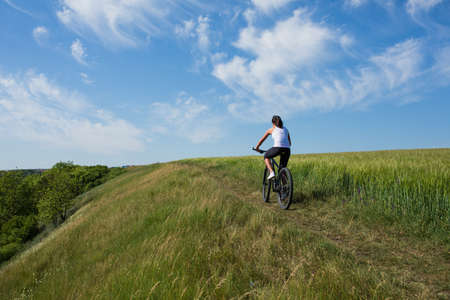 Fit woman going for bike ride on a sunny day in the countryside