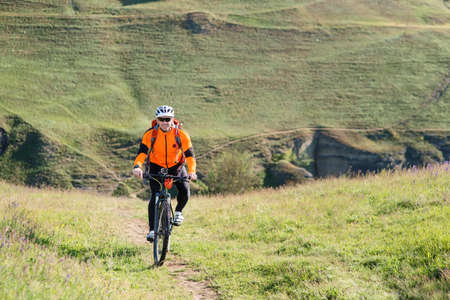 Cyclist in orange jersey on the Beautiful Meadow Trail